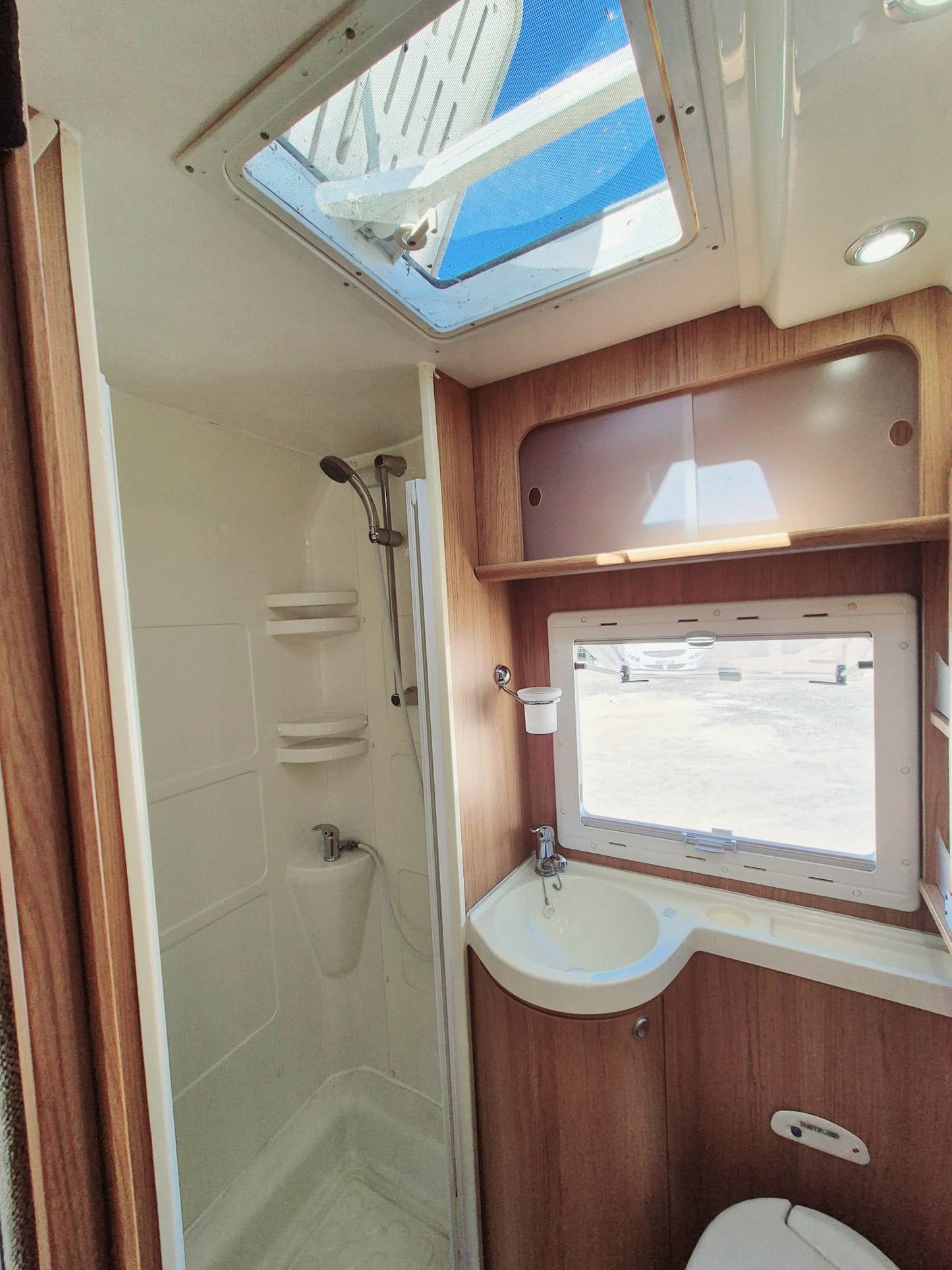 Baño amplio en autocaravana equipada en Tenerife, con ventana, lavabo y armario.